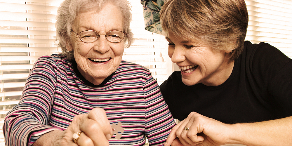 Young woman and older woman doing a puzzle  Young woman and older woman doing a puzzle